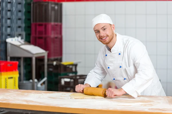 Panettiere con rotolo di pasta che lavora in panetteria — Foto Stock