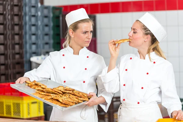 Baker, okusování čerstvé pečivo z zásobníku v pekárně — Stock fotografie