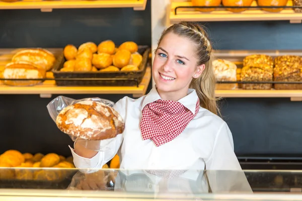 Butiksägare i bageri presentera limpa bröd till klient — Stockfoto