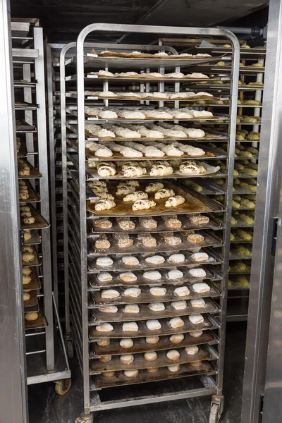 Cremalheira de padaria com massa de pão fresca no refrigerador Fotografia De Stock