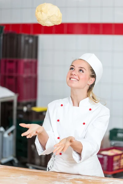 Baker in bakkerij deeg overgeven in de lucht Stockfoto