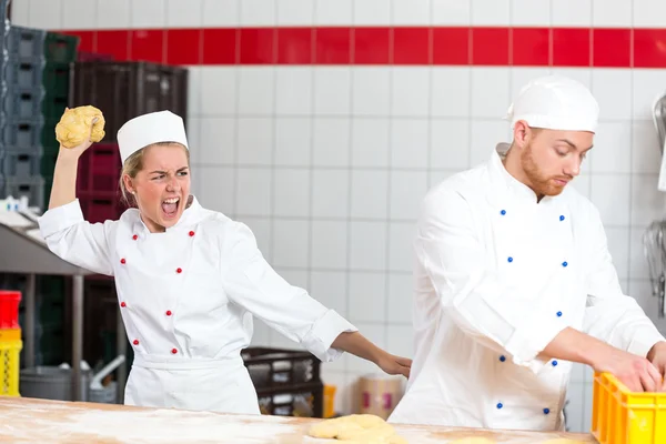 Baker, který je frustrovaný s kolega házení těsto na něj Stock Fotografie