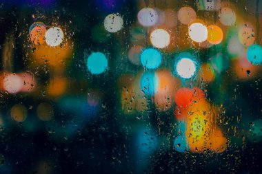 Yağmurlu bir gece, pencereye yağmur damlaları, renkli ışıklar, yağmur ve bokeh. Yüksek kalite fotoğraf