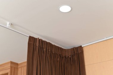 Tavandan sarkan kahverengi perdeli modern ev dekorasyonu ayrıntıları. durgun ışık sakin ve şık yaşam alanı için rahat pencere dekorasyonunu aydınlatır