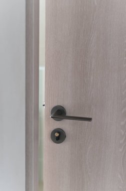 Kısmen açık ahşap kapılı modern metal kulplu minimalist hafif ahşap desenli iç mahremiyet çağdaş dikey nötr renk.