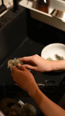 Odaklanmış Asyalı kadın ev yaşamından zevk alıyor, taze yemek hazırlıyor. Rahatlamak ve kişisel refahına odaklanmak için bir şans. Mutfak lavabosunda dikkatli deniz ürünleri hazırlamak için.