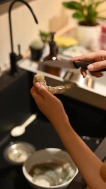 Sakin Asyalı kadın sağlıklı ev hayatı yaşıyor. Mutfakta taze karides hazırlamanın günlük rutini rahatlama, refah ve kendine bakmanın bir şekli haline gelir.