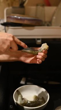 Sağlıklı ev yaşamını kucaklayan Asyalı bir kadın, taze karides yemeği hazırlarken nasıl rahatlayacağını ve mutluluğu nasıl bulacağını gösterir.