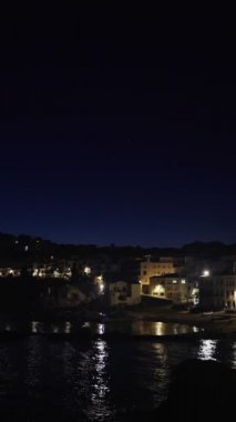 Dikey. Akşamları güzel Akdeniz köyü. Deniz kıyısındaki küçük bir kasabanın gece manzarası. İspanya 'da Calella de Palafrugell' in su ve ışıkları. Costa Brava tatili soğuk. Beyaz evler 