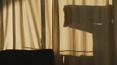 Çamaşırhanede takılan bir adamın silüeti. Ev ödevi. Güneşin altında temiz çamaşırları kurutmak. Güneşli bir günde karşıt gölgeler. Beyaz perdelerin arkasında bir adamın gölgesi. Kıyafetler için kurutucu.