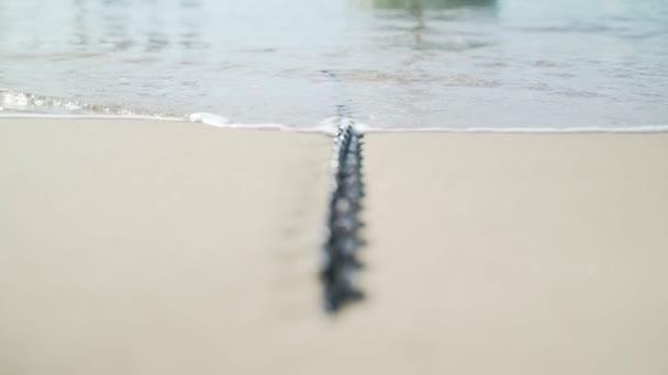 Lätt bris på havet. Vågor löper på en båtkedja som ligger på sanden. Transparent havsvatten i den gamla båthamnen. Vintage. Solsken och lätta ringar på vattenytan. Lugn och ro. — Stockvideo