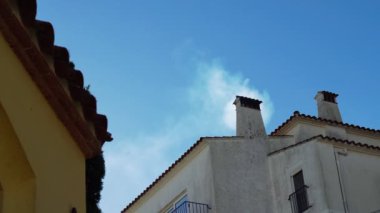 Köydeki eski bir evin bacasından dumanlar yükseliyor. Açık kış günü. Mavi gökyüzüne karşı Akdeniz Beyaz Sarayı. Şömine. Mutfaktan duman geliyor. Beyaz duvarlar ve fayanslı çatı.