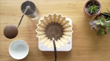 Kahve yapıyorum. Evdeki özel kahve. Barista çaydanlıktan kahve damlatıcısına su döker. Aromatik filtre kahve masada. Seramik huni, cam sunucu ve filtre kağıdı. Üst görünüm