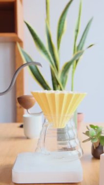 Kahve yapıyorum. Evdeki özel kahve. Barista çaydanlıktan kahve damlatıcısına su döker. Aromatik filtre kahve masada. Seramik huni, cam sunucu ve filtre kağıdı. Dikey 