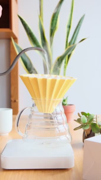 Je fais du café. Café spécial à la maison. Barista verse de l'eau de la bouilloire goutte à goutte dans le goutteur de café. Café filtre aromatique sur la table. Entonnoir en céramique, serveur en verre et papier filtre. Vertical — Video