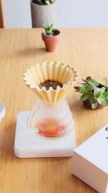 Kahve yapıyorum. Evdeki özel kahve. Barista çaydanlıktan kahve damlatıcısına su döker. Aromatik filtre kahve masada. Seramik huni, cam sunucu ve filtre kağıdı. Dikey 
