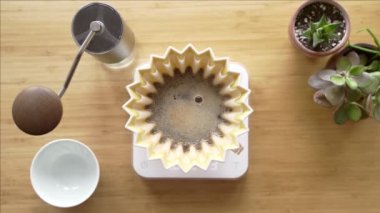 Kahve yapıyorum. Evdeki özel kahve. Barista çaydanlıktan kahve damlatıcısına su döker. Aromatik filtre kahve masada. Seramik huni, cam sunucu ve filtre kağıdı. Üst görünüm