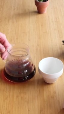 Kahve yapıyorum. Evdeki özel kahve. Barista kahve sunucusundan beyaz fincana su döküyor. Aromatik filtre kahve masada. Seramik huni ve cam sunucu. Kahvaltıda. Kahve molası.