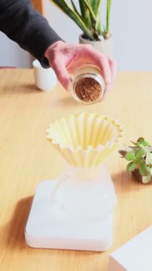 Kahve yapıyorum. Evde özel kahve. Barista kahve damlatıcısına taze öğütülmüş kahve dolduruyor. Aromatik filtre kahve masada. Seramik huni, cam sunucu ve filtre kağıdı. Öğütücü.