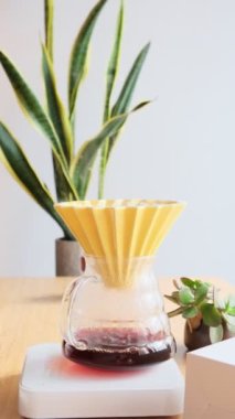 Kahve yapıyorum. Evdeki özel kahve. Barista çaydanlıktan kahve damlatıcısına su döker. Aromatik filtre kahve masada. Seramik huni, cam sunucu ve filtre kağıdı. Dikey 