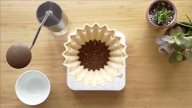 Kahve yapıyorum. Evdeki özel kahve. Barista çaydanlıktan kahve damlatıcısına su döker. Aromatik filtre kahve masada. Seramik huni, cam sunucu ve filtre kağıdı. Üst görünüm