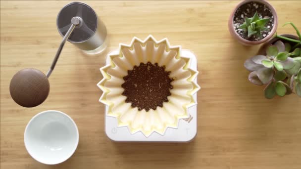 커피만드는 거. 집에 있는 커피. 바리스타는 드립 주전자에서 물을 커피 드레이퍼에 붓습니다. 탁자 위에 있는 Aromatic filter coffee. 세라믹 깔때기, 유리 서버, 필터 페이퍼. 위에서 본 풍경 — 비디오