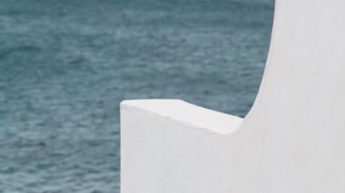 Beyaz duvarın içinden güzel bir deniz manzarası. Açık mavi su, ışık dalgaları ve güneş parlaması. Yaz güneşli bir gün. Denizde bir tatil. Sakin ol ve rahatla. Mimari detay. Eylem. İnanılmaz deniz manzarası..