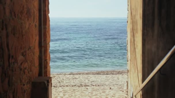 Молодая женщина в широких черных штанах и шляпе ходит по пляжу. Солнечный день в море. Вид со старой полосы. Теплый отдых на золотом пляже. Летний холод. Белый песок, синее море и чистое небо. — стоковое видео
