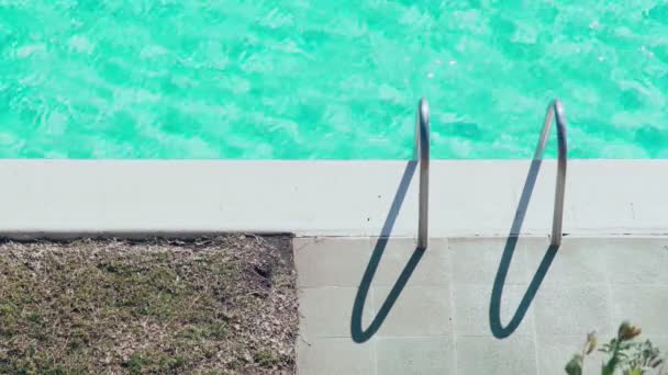 Beautiful light ripples on the water surface in the pool. Sun glare on turquoise water. Hot sunny day by the swimming pool. Summer chill. Holidays. Vacation. Handrails. Relax and calmness. — Stock Video