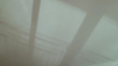 Tavanda ve duvarlarda güzel soyut gölgeler var. Pencerenin gölgeleri ve balkon korkulukları titriyor. Beyaz bir duvarda hareket eden siluetler. Suyun yansımaları beyaz bir yüzeyde dalgalanır..