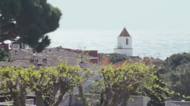 Deniz manzarası ve kıyı köyünün çatıları çok güzel. Döşemeli çatılar ve kilisenin beyaz çan kulesi. Yaz güneşli bir gün. Denizde bir tatil. Sakinlik ve rahatlama. İnanılmaz deniz manzarası..
