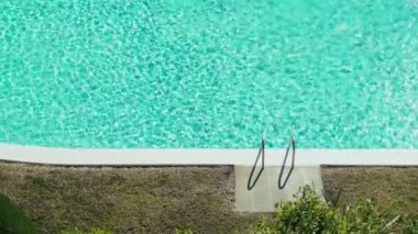 Havuzun su yüzeyinde çok güzel ışık dalgaları var. Turkuaz suda güneş parlıyor. Yüzme havuzunun yanında sıcak güneşli bir gün. Yaz soğuğu. Tatillerde. Tatilde. Tırabzanlar. Rahatla ve sakinleş..