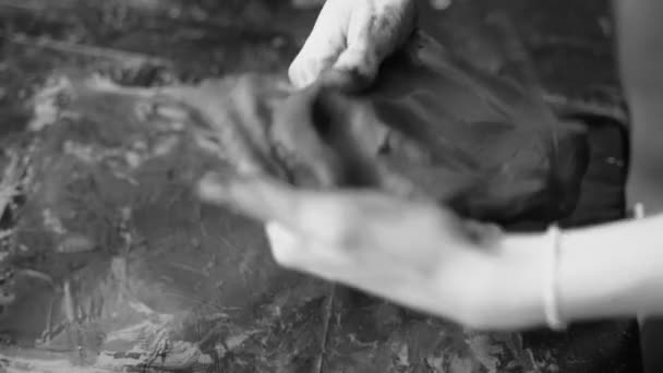 Close-up de mãos femininas trabalhando com argila. Potter em processo de escultura. Moldar um produto de argila. Argila escura. Vídeo em preto e branco. Oficina de cerâmica. O artista esculpe a partir de uma massa plástica escura. — Vídeo de Stock