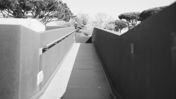 Hombre con capucha corriendo a través de un hermoso paisaje urbano. Mañana correrá por la ciudad. Deportes y estilo de vida saludable. Atleta en el estacionamiento. Deporte urbano. Haga ejercicio al aire libre en un día soleado. Blanco y negro — Vídeos de Stock