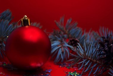 Yuvarlak Noel oyuncak topu, mesaj ya da logo için yeri var. Noel kompozisyonu. Kırmızı arka planda Noel oyuncakları ve ladin dalları yakın plan.