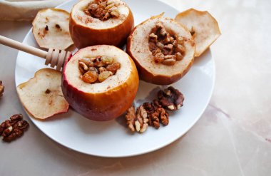 Cevizli, kuru üzümlü ve ballı fırında elmalar hafif mermer arka planda bir tabakta.