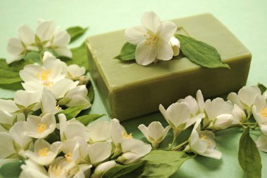 Kompozisyon, köşedeki çerçeve, yasemin çiçeklerinden oluşuyor. Yeşil arka planda doğal el yapımı sabun. Spa tedavileri. Yeşil arka planda yasemin olan organik sabun. Doğal kozmetik ürünleri, eko yaşam tarzı.