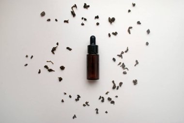 Kuru yeşil çayla çevrili bir kavanoz çay serumu. Çay ağacı yağı..