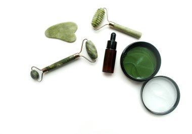 Jade Stone yüz masajı seti. Göz bantları, serum. Beyaz arkaplan, model, metin için yer.