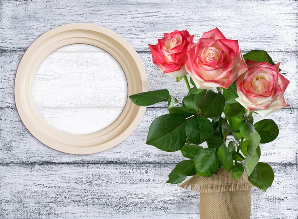 Roses and round photo frame on background of shabby wooden plank — Stock Photo, Image