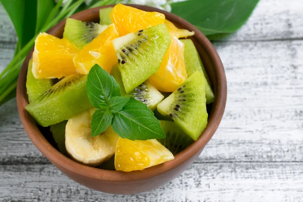 Ensalada de frutas con kiwi, plátano, naranja y menta en el bowl —  Fotos de Stock