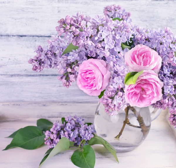 Boeket van lila bloemen en rozen in glazen fles — Stockfoto