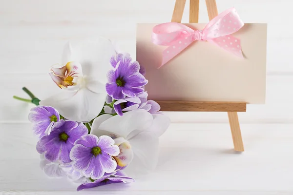 Strauß Veilchenprimeln mit Orchidee und Papier-Grußkarte — Stockfoto