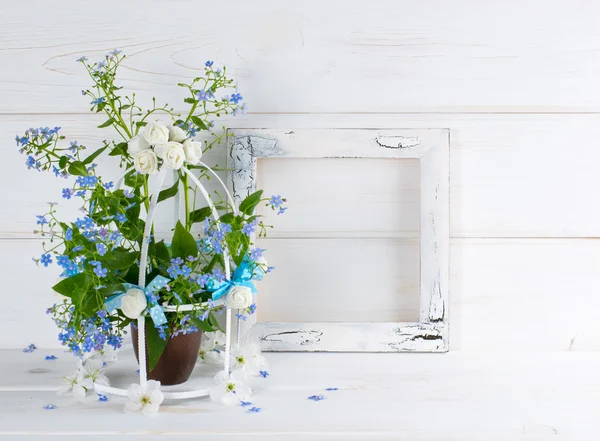 Förgätmigej blommor med fågelbur och foto ram — Stockfoto