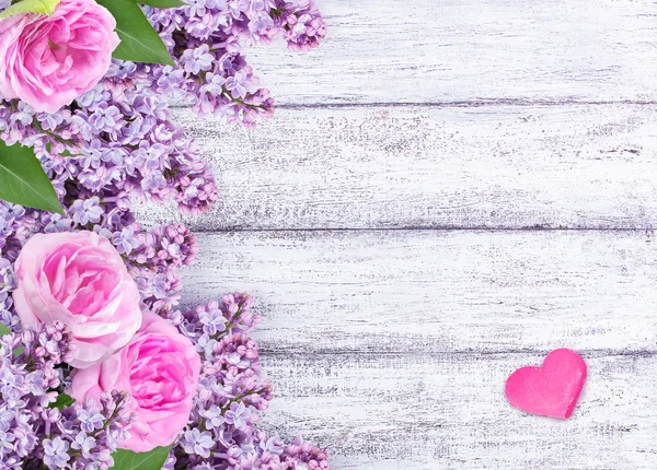 Flores de lilás com rosas e dois corações em tábuas de madeira rasgadas — Fotografia de Stock
