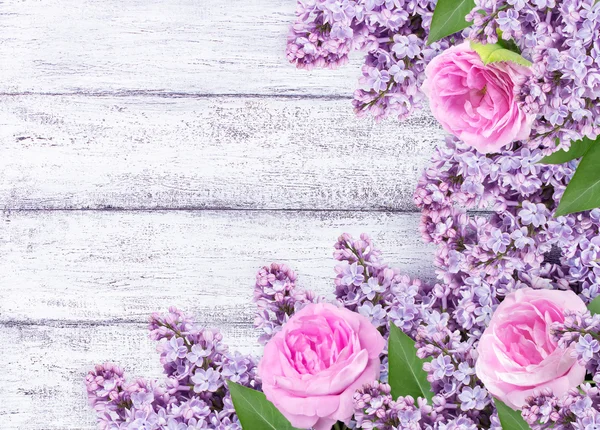 ぼろぼろの木板にバラとライラックの花 — ストック写真