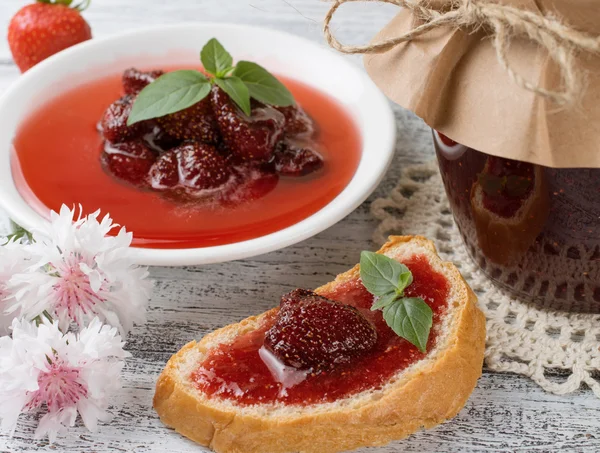 Erdbeerkonfitüre in Dosen und Marmeladensandwich auf dem Holzbrett — Stockfoto