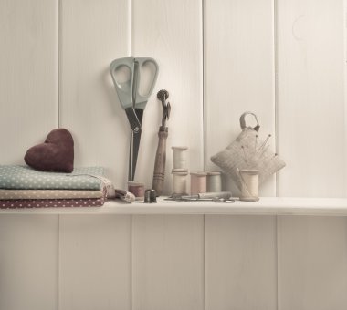 Set of tools for sewing and fabric lying on the wooden shelf. In clipart