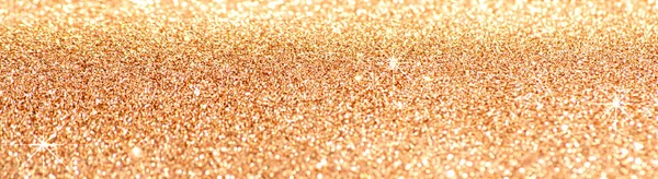 Shining glowing luxury gold background with shiny sparkling bokeh and macro magic golden glitter sparkles abstract texture closeup, wide panoramic banner