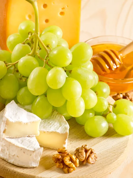 Still life of cheese, honey, walnuts and grapes — Stock Photo, Image